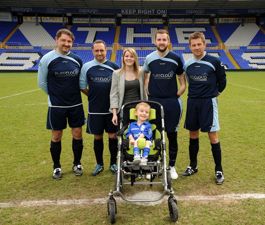 Football team posing with Harrison and his mom for the Helping Harrison initiative.