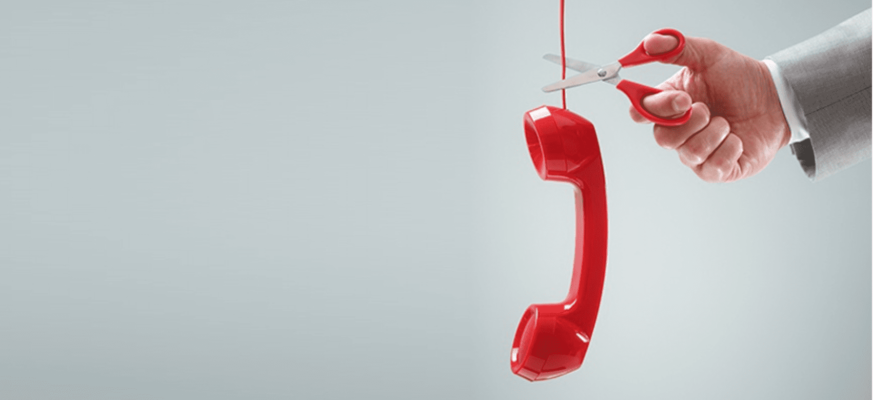 Hand cutting the cable of a red phone with scissors, illustrating the upcoming ISDN switch-off.