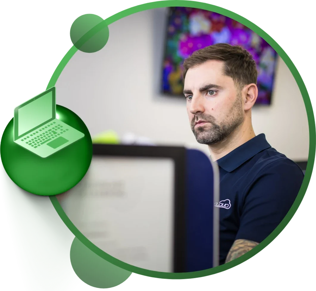 Man with a focused expression working at a computer, wearing a navy blue shirt.