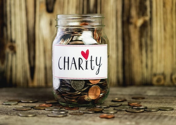 Jar filled with coins labeled ‘Charity’ for International Charity Day.