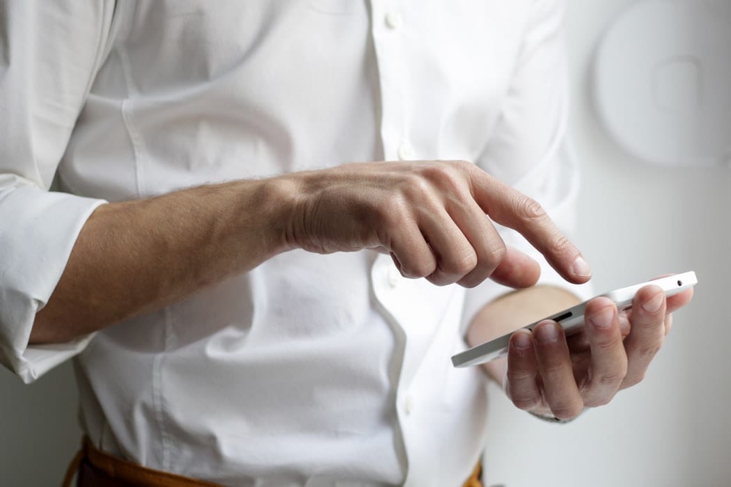 Man in a white shirt, using his smartphone
